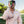 Man in pink long-sleeve shirt holding a smartphone with a golf club on a golf course